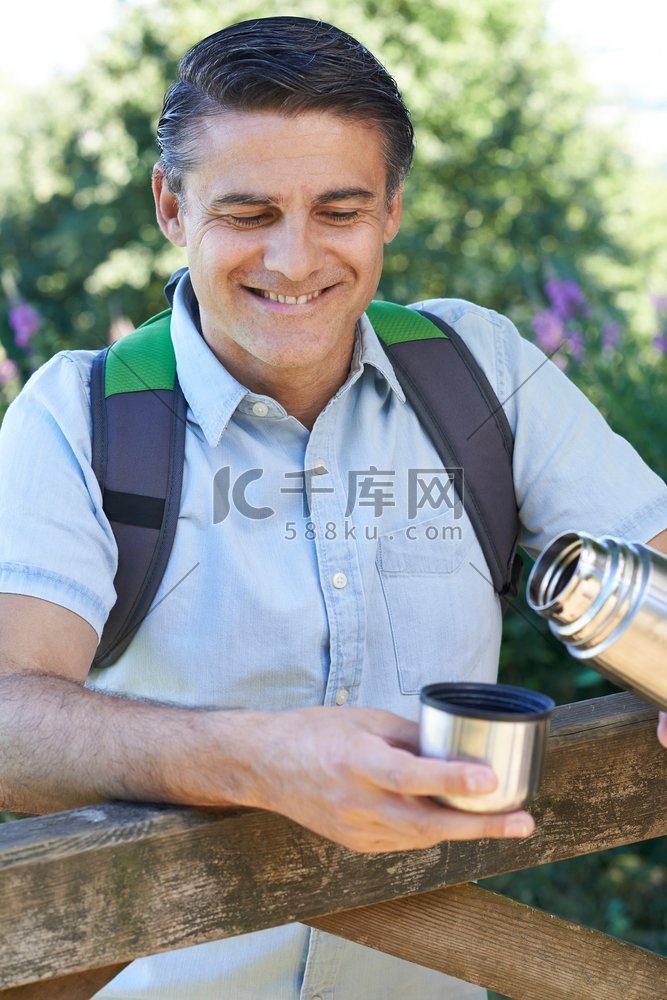 走在路上的成熟男人从烧瓶里倒热