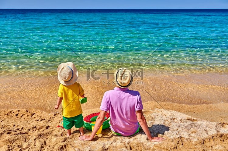 两岁的小男孩和父亲在海滩上。充