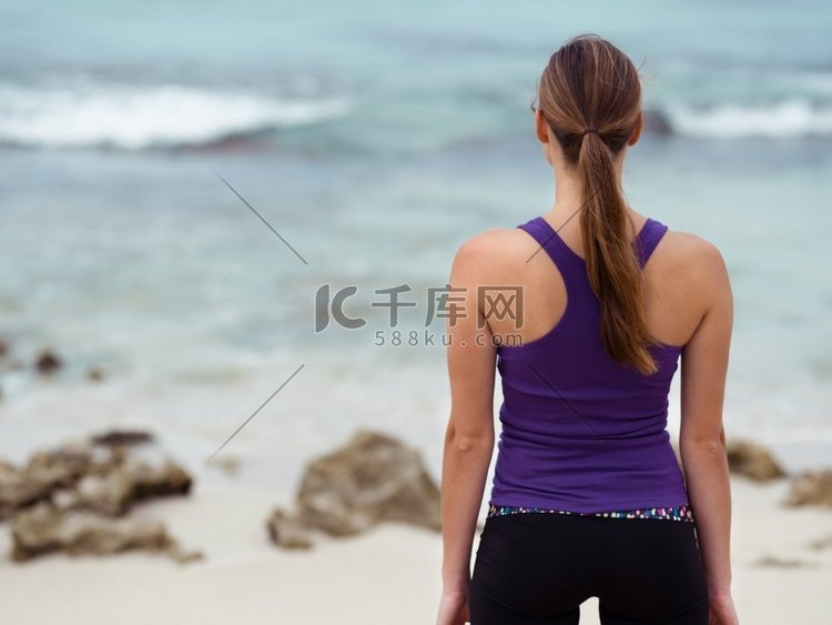 运动的年轻女子站在海边