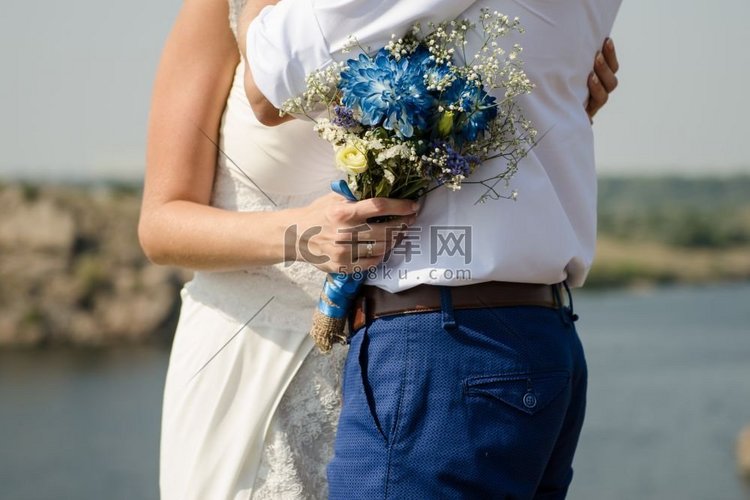 新娘拥抱新郎，手持印有蓝色花朵