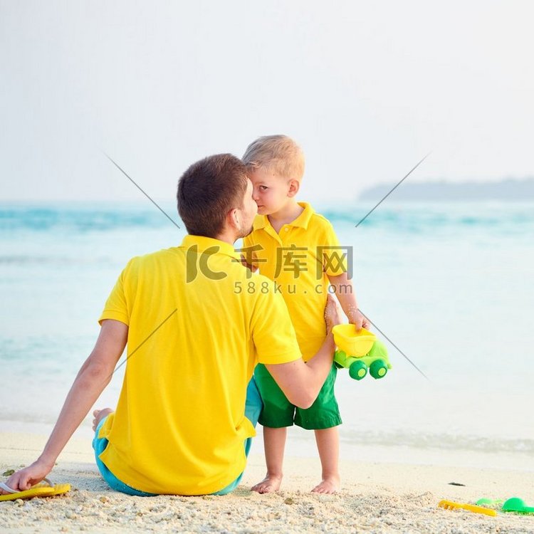三岁的小男孩和父亲在海滩上。暑