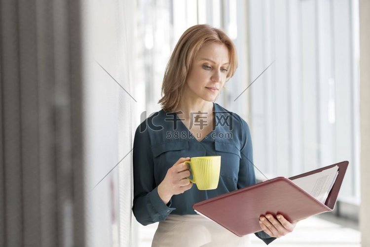 女商人阅读文件有咖啡在办公室