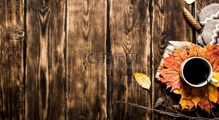 一杯热咖啡加秋天的叶子。在木制