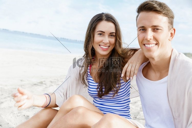 浪漫的年轻情侣坐在海滩上。浪漫