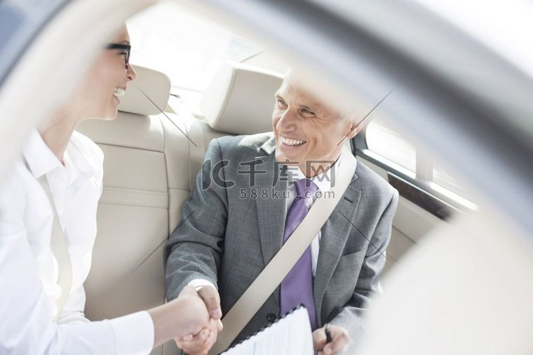 微笑的商业伙伴握手，而坐在车里