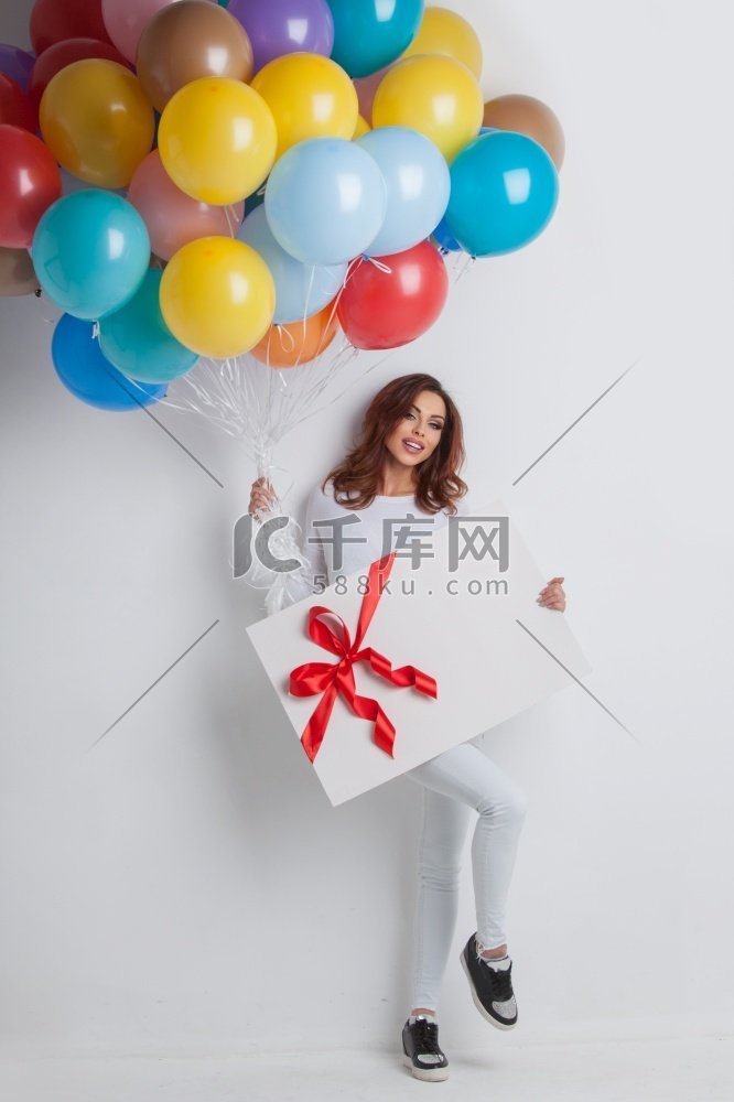 年轻的微笑的妇女与气球和大礼品