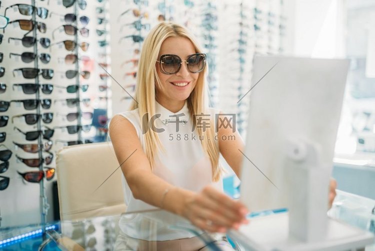 戴太阳镜的女顾客在光学商店看镜