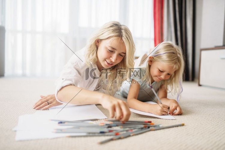 母亲和孩子躺在地板上画画。亲情