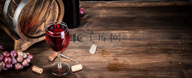 桌上放着一杯红葡萄酒。背景是木