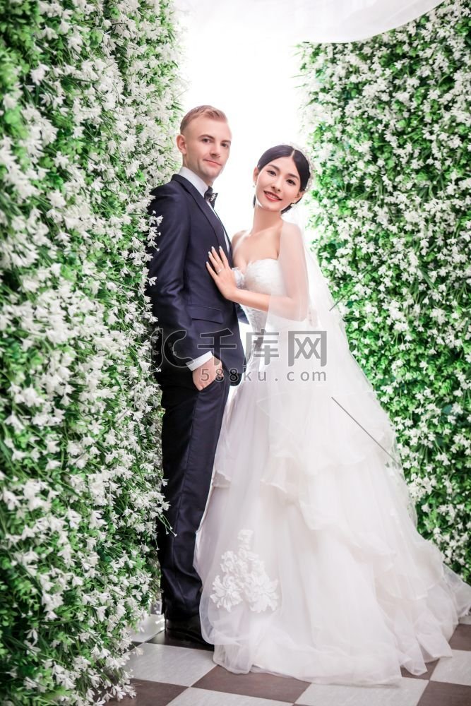 站在鲜花装饰中的浪漫婚礼夫妇的