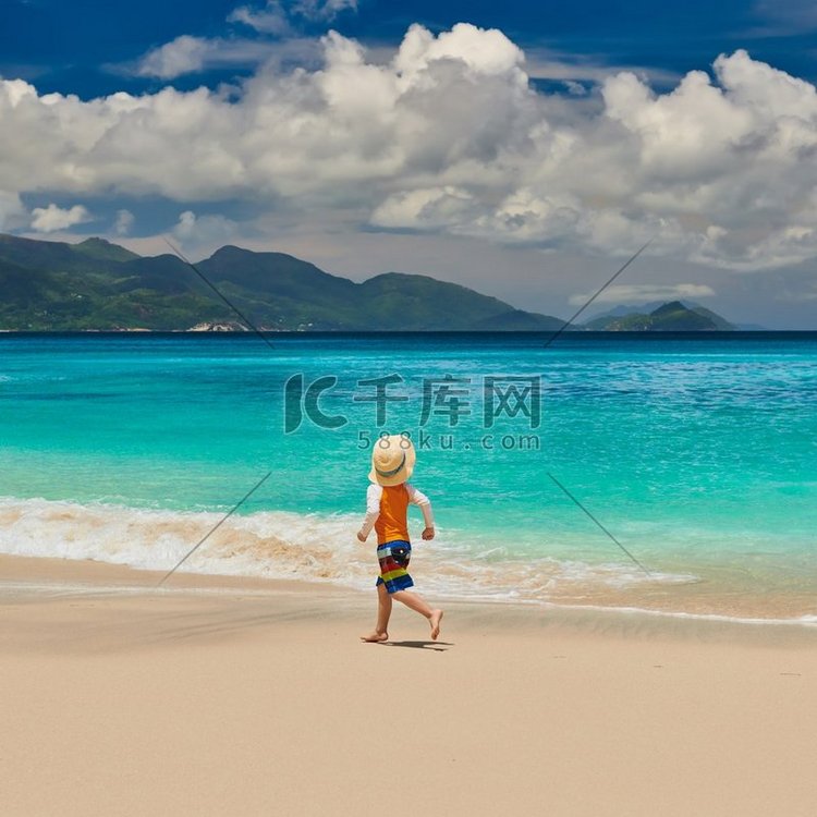 三岁的蹒跚学步的男孩在海滩上奔