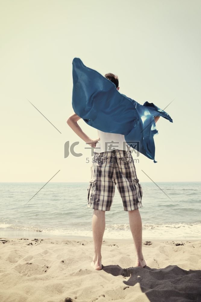 滑稽的超级英雄站在炎热的沙滩上