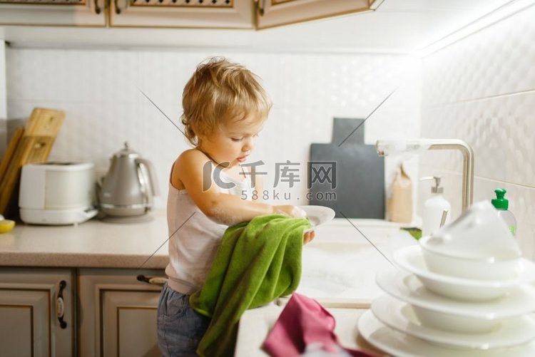 一个小女孩在厨房里擦盘子。宝宝