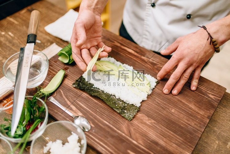 男厨师做寿司卷在木桌，海鲜。传