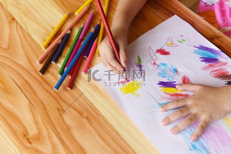 女孩绘画在纸上与彩色铅笔在家里