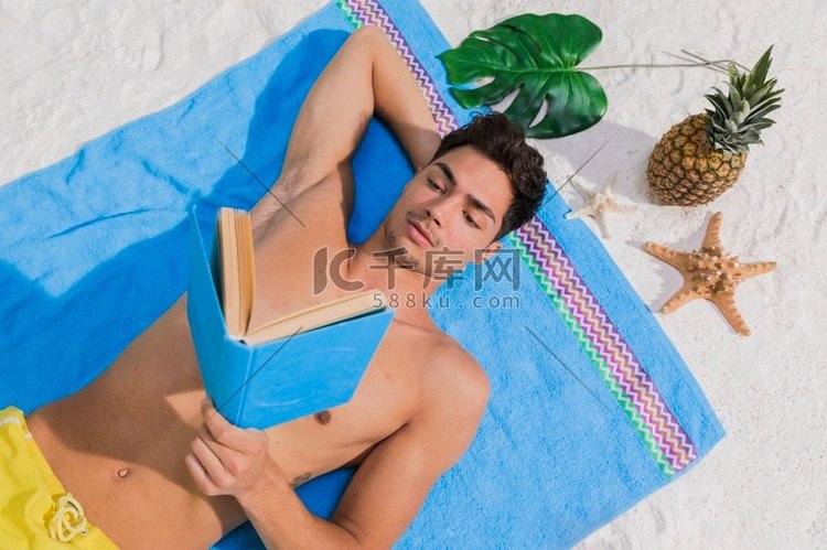 有吸引力的年轻人读书海滩