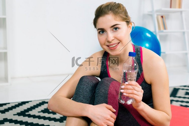 肖像快乐的年轻女子拿着塑料水瓶