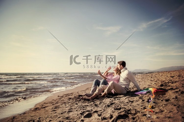 一对年轻的情侣在秋日的海滩上玩