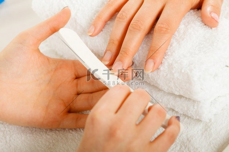 女人的手放在毛巾上，美容师锉指