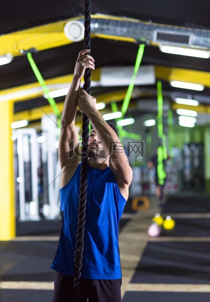 年轻肌肉男做绳索攀登交叉健身房