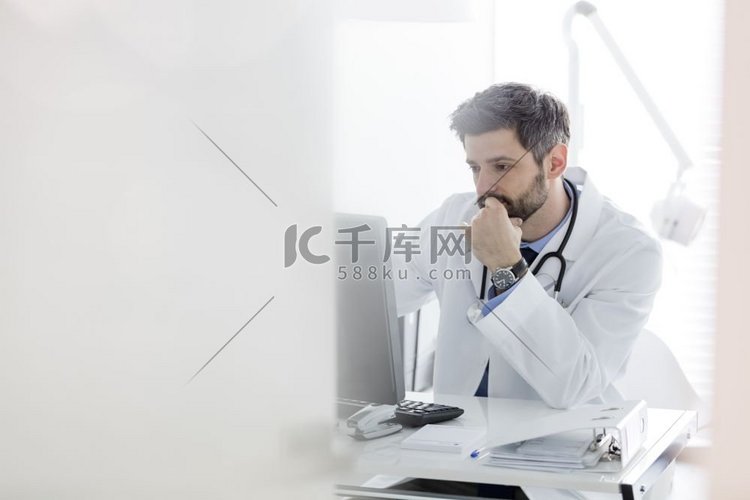 严重的医生使用电脑在办公桌在医