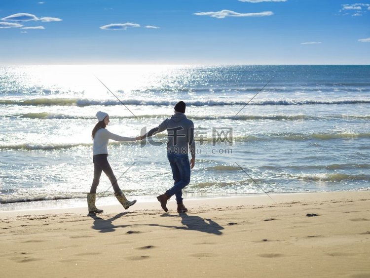 年轻夫妇有乐趣散步和拥抱在海滩