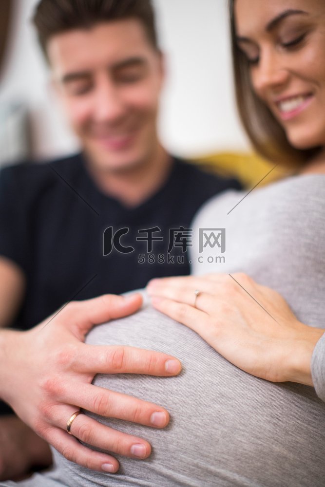 怀孕的夫妇坐在沙发上与男人触摸
