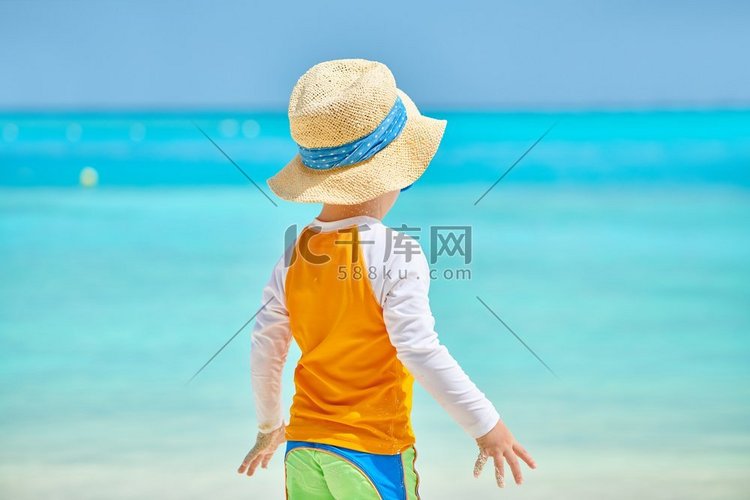 海滩上三岁的蹒跚学步的男孩。暑