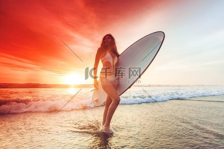 妇女剪影在热带海滩举行冲浪板在