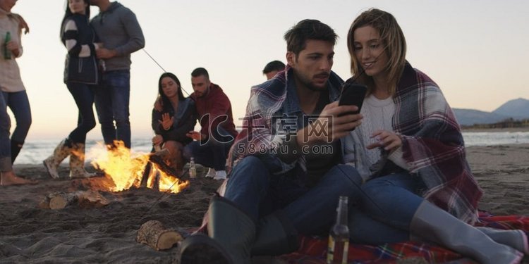 一对情侣在海滩派对上用手机和朋