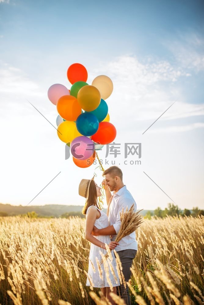 愉快的爱情夫妇与气球拥抱在麦田