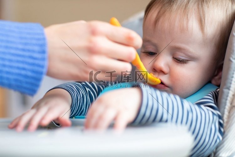 坐在高脚椅上的爱挑剔的小男孩吃