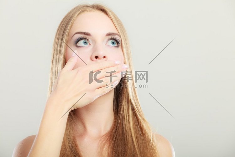年轻的惊讶的妇女覆盖她的嘴用手