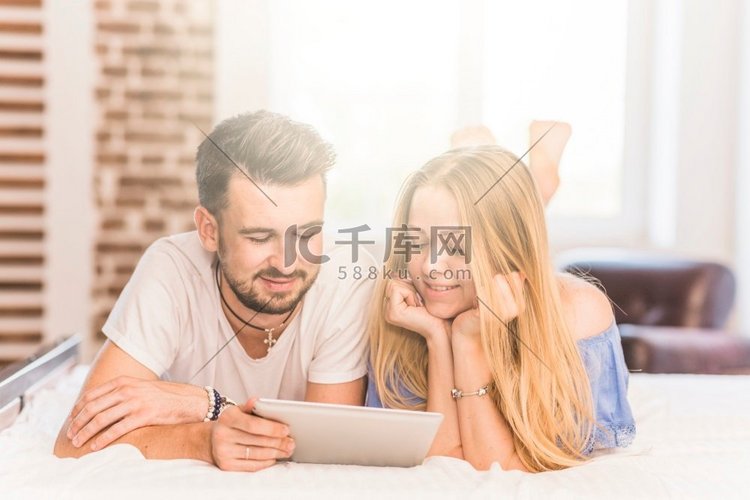 微笑的年轻夫妇躺在床上寻找数字