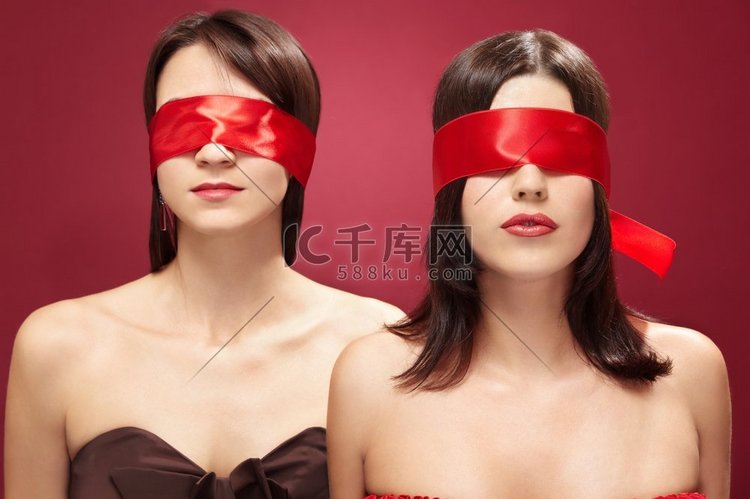 两个迷人的女孩蒙眼睛在一个红色