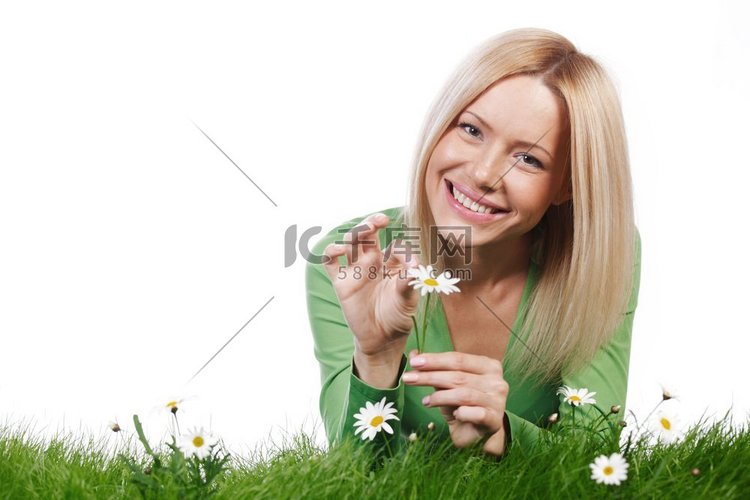 快乐的年轻妇女躺在草与洋甘菊花