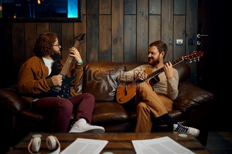 两个男性朋友一起在家弹吉他。音