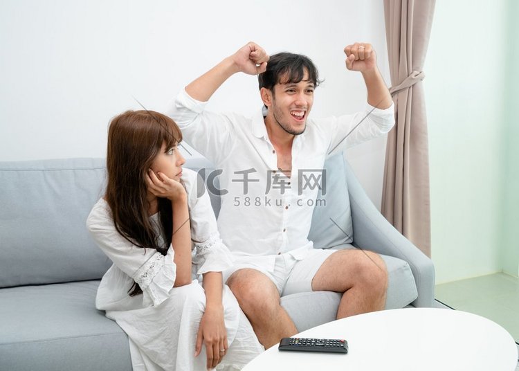 快乐的年轻夫妇看电视在沙发上在