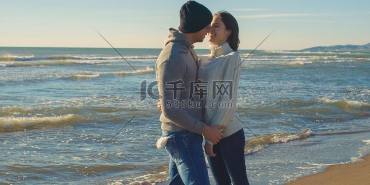 凉爽的夫妇笑和拥抱在海滩前面在