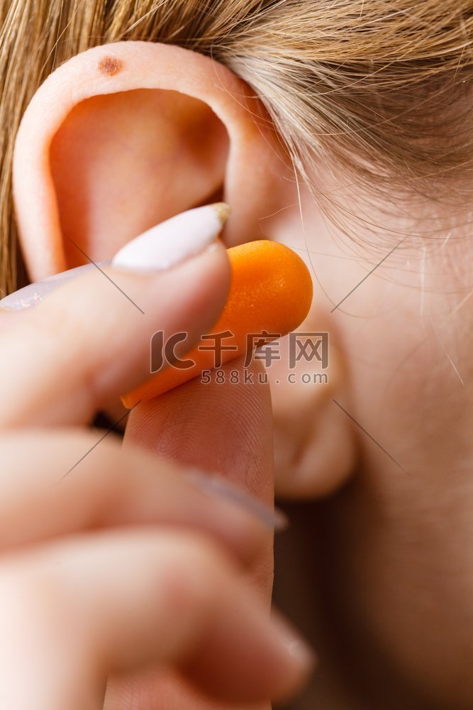 女人把耳塞放进她的耳朵摆脱噪音