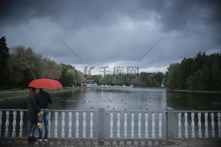 雨在秋天公园/年轻的25岁夫妇