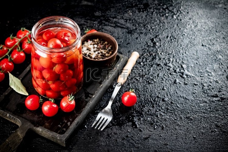 腌番茄放在砧板上的玻璃罐里。黑