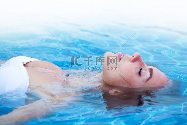 女孩在比基尼放松漂浮在游泳池的