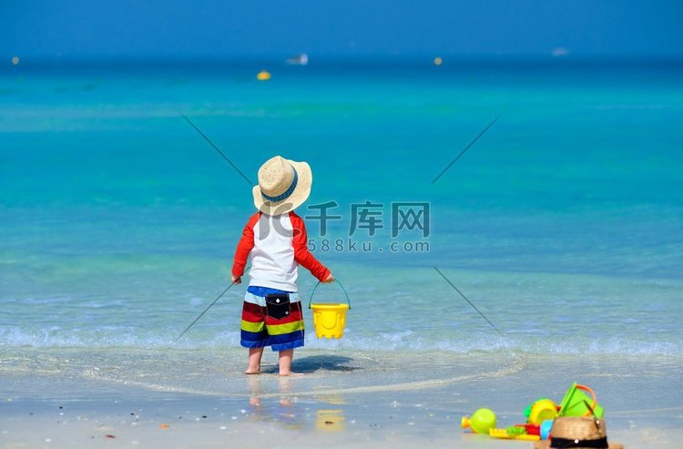 两岁的蹒跚学步的男孩在海滩上玩
