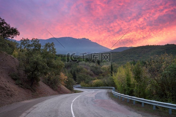 山路蜿蜒穿过森林，在夏日的夕阳