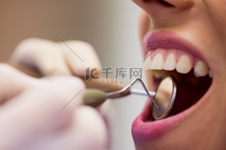 特写的牙医检查一个女病人与工具