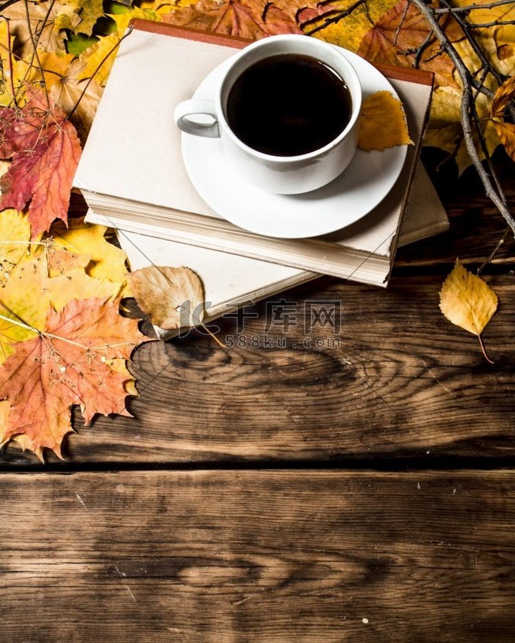 一杯咖啡配一本旧书和枫叶。在木