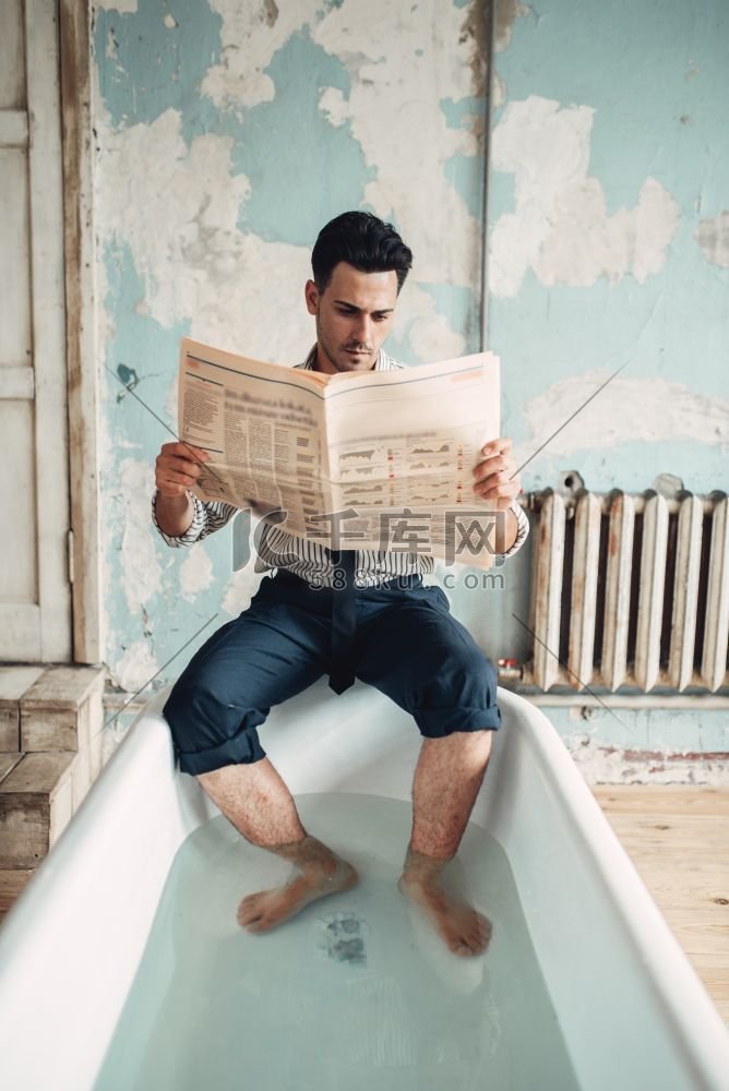 一个滑稽的商人坐在浴缸边上看报