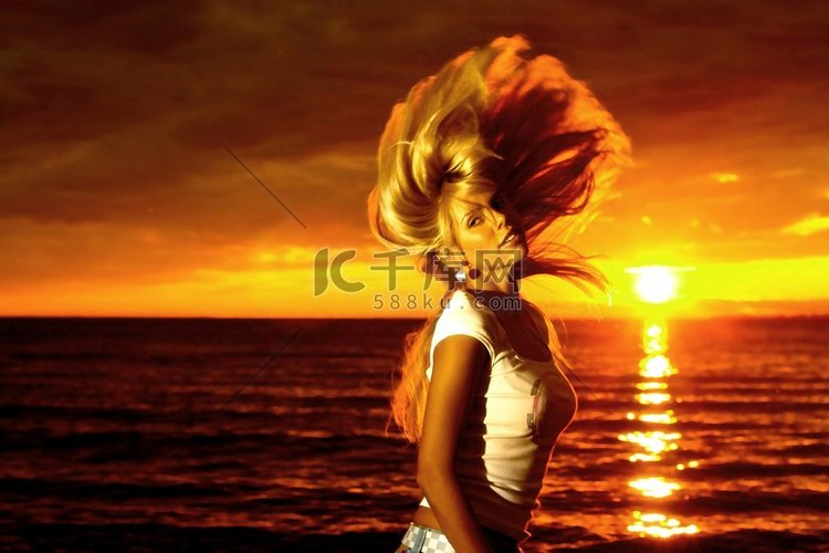 美丽的女孩头发在海上金色的夕阳