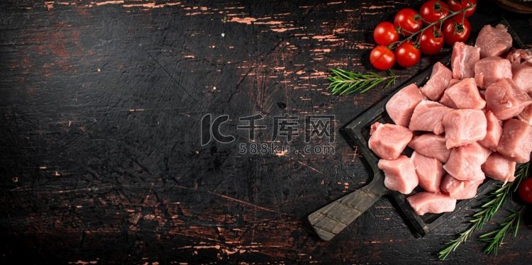 切板上的生猪肉和西红柿。黑色背